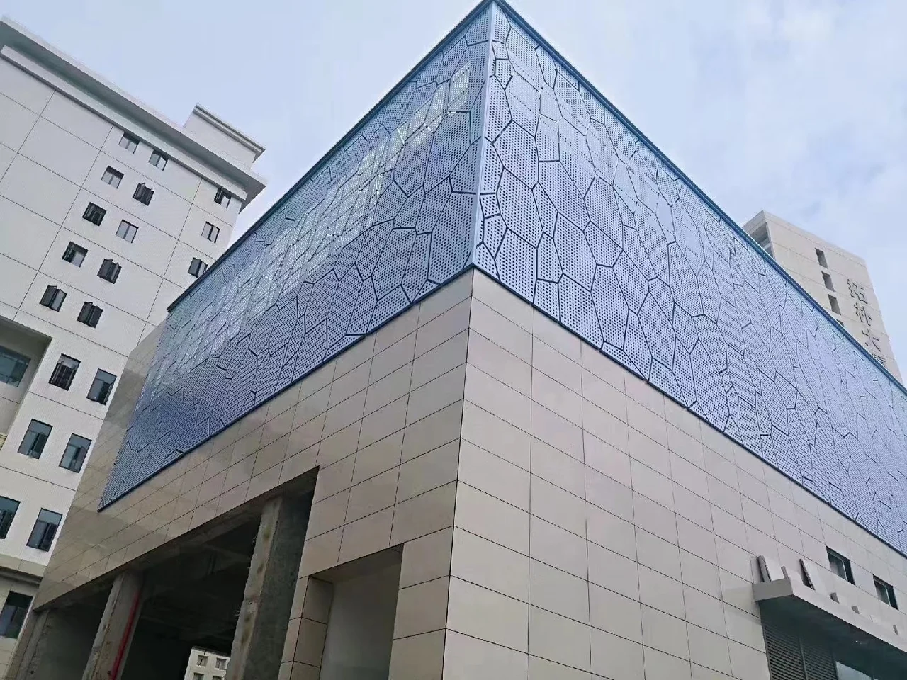 Perforated facade screen above solid wall panels at a building corner