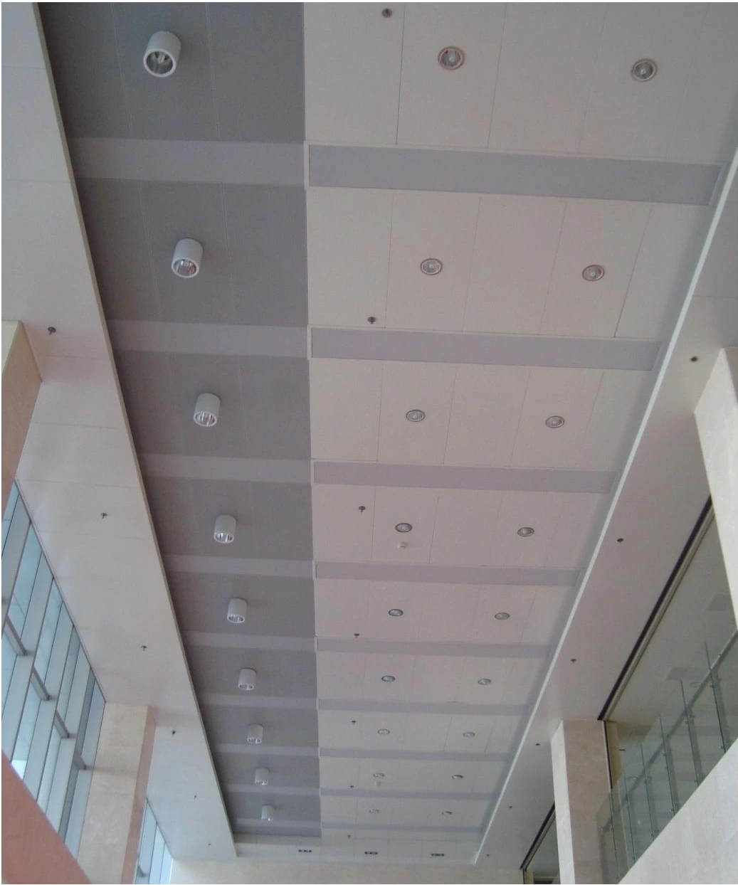 Rectangular ceiling bays and round downlights above a glazed interior walkway in Hefei
