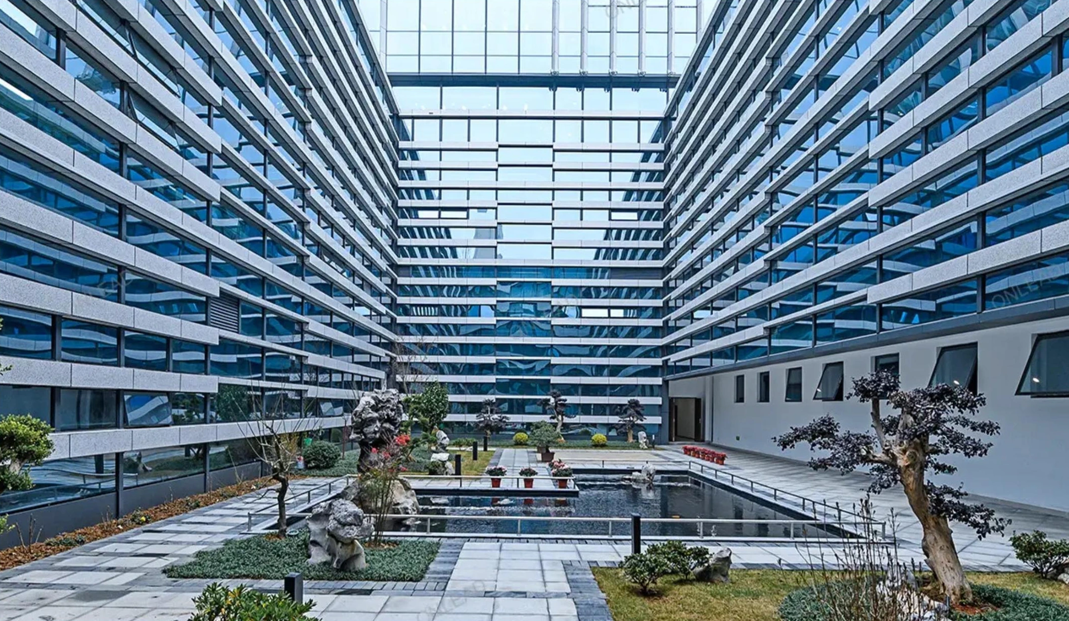Horizontal facade bands overlooking a landscaped office courtyard in Anqing