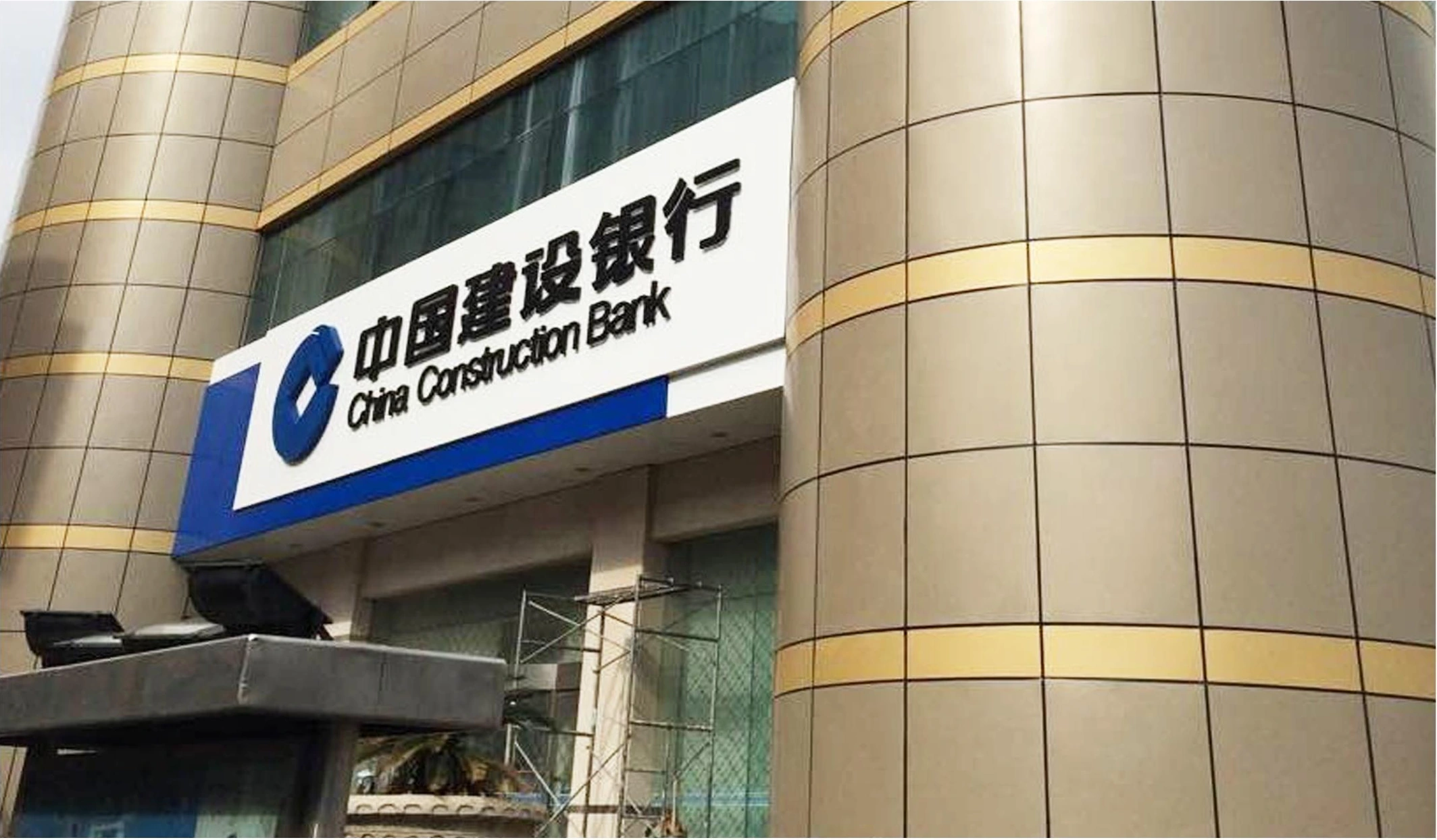 Curved gold-toned metal facade panels and recessed joints at a bank entrance in Zhoushan