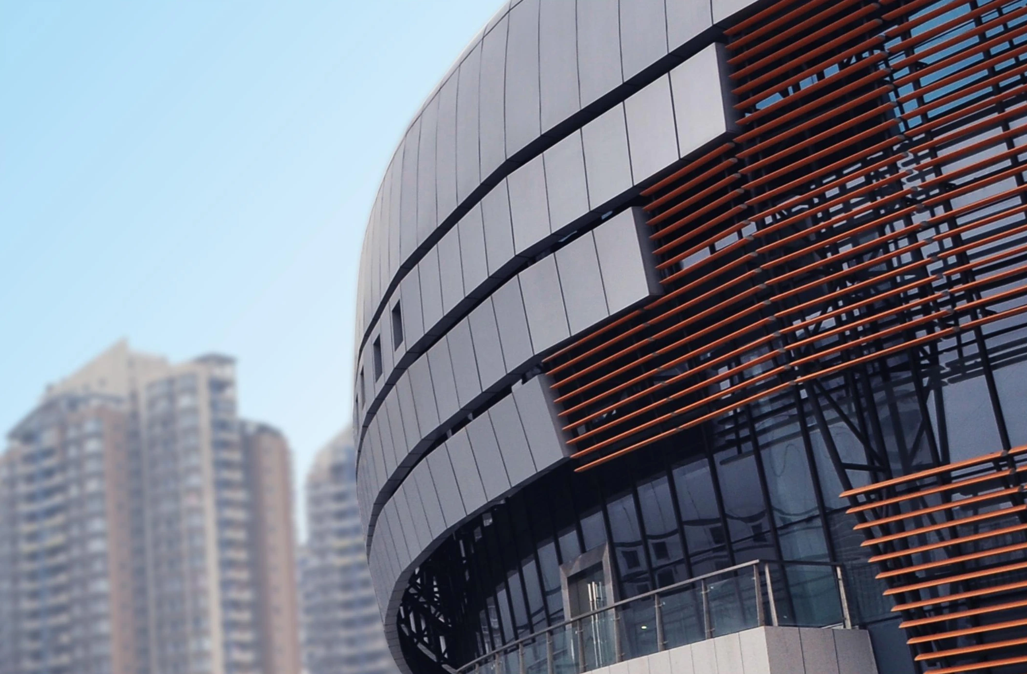 Bronze-toned horizontal facade louvers around a curved sports building in Chongqing