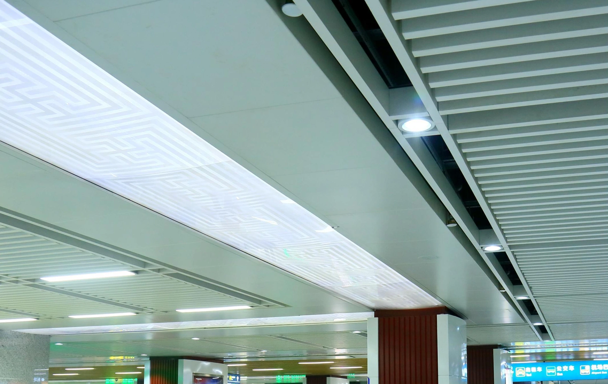 Illuminated geometric ceiling panel beside linear louvers at a Guiyang airport terminal
