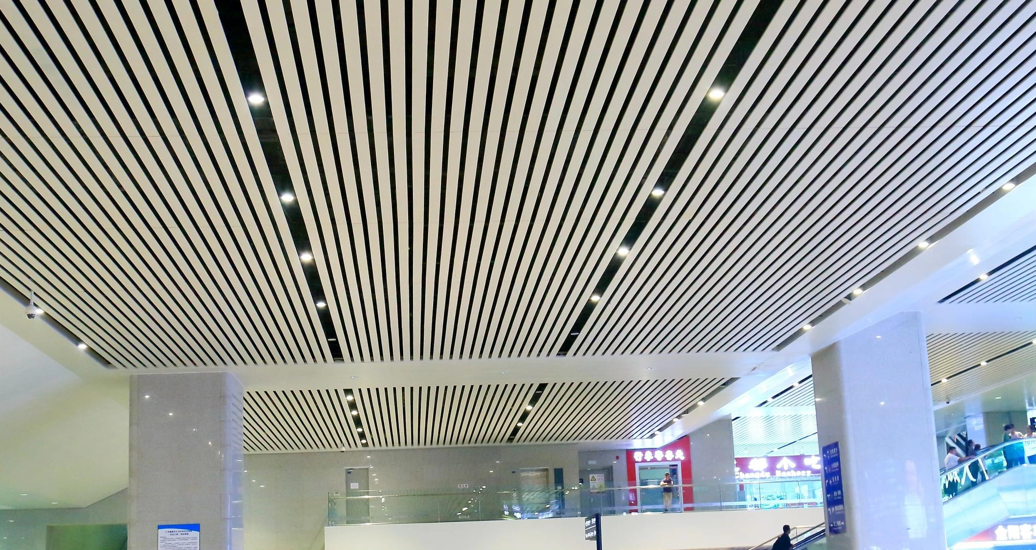 Parallel aluminum ceiling fins and recessed lighting in a Guiyang railway station hall