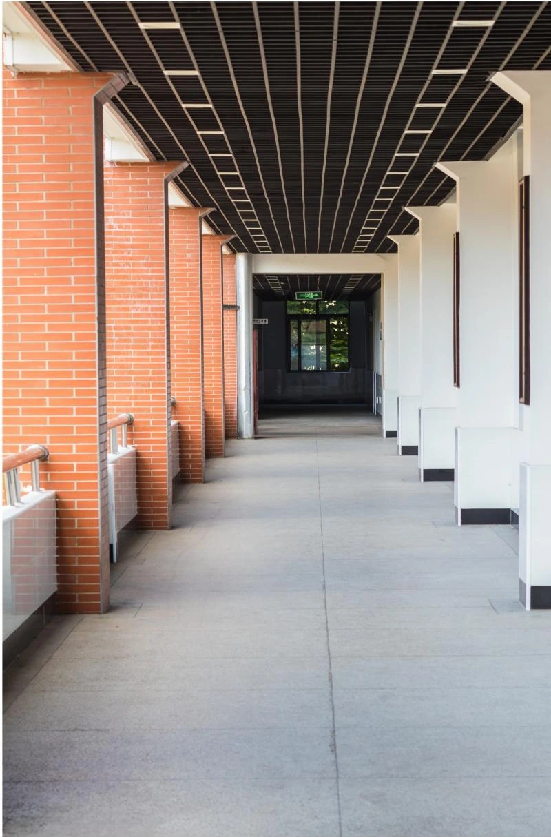 Wood-look linear ceiling above a brick-lined school corridor in Hangzhou
