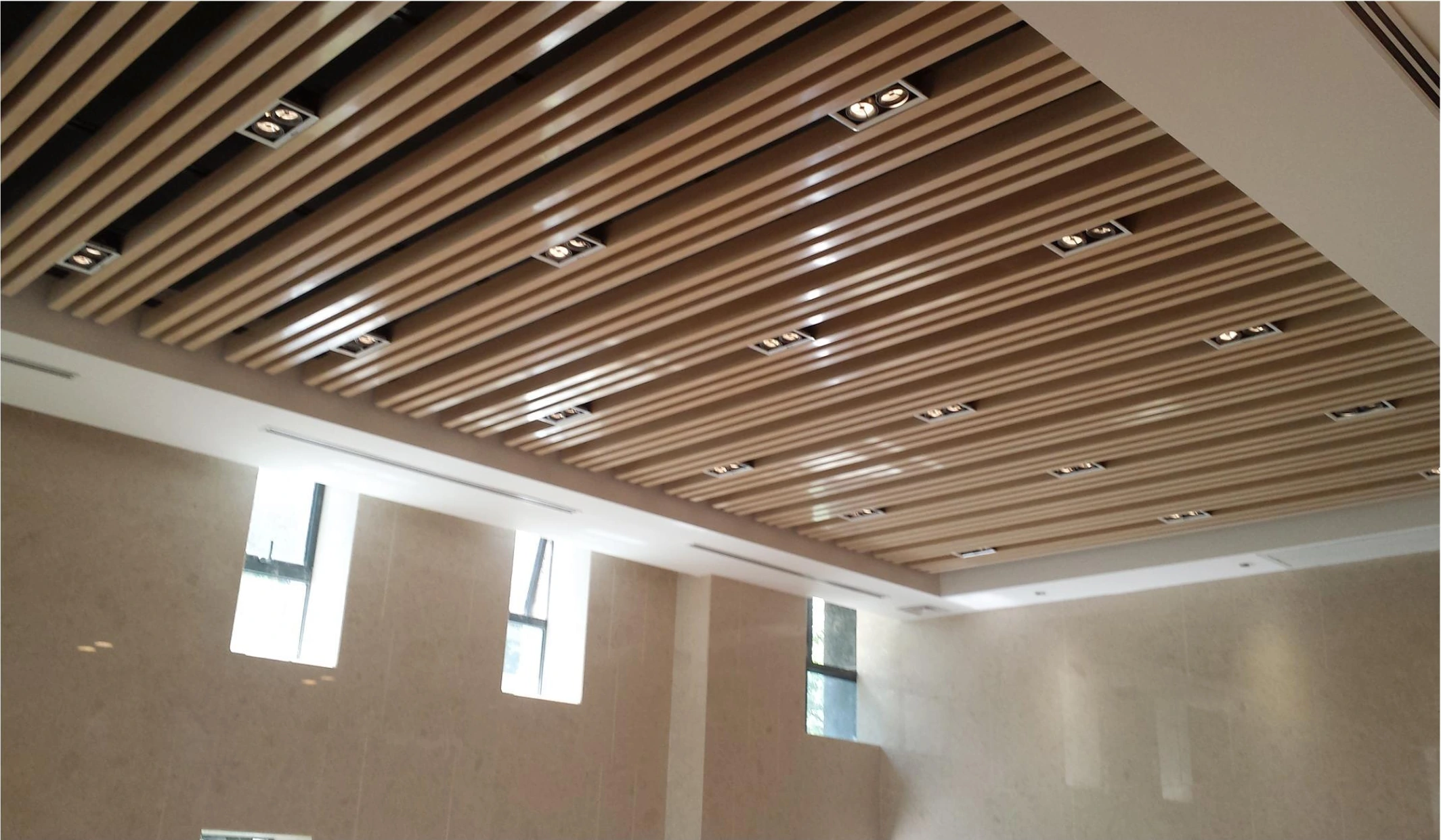 Wood-look linear aluminum ceiling with recessed spotlights in an office lobby in Nanjing