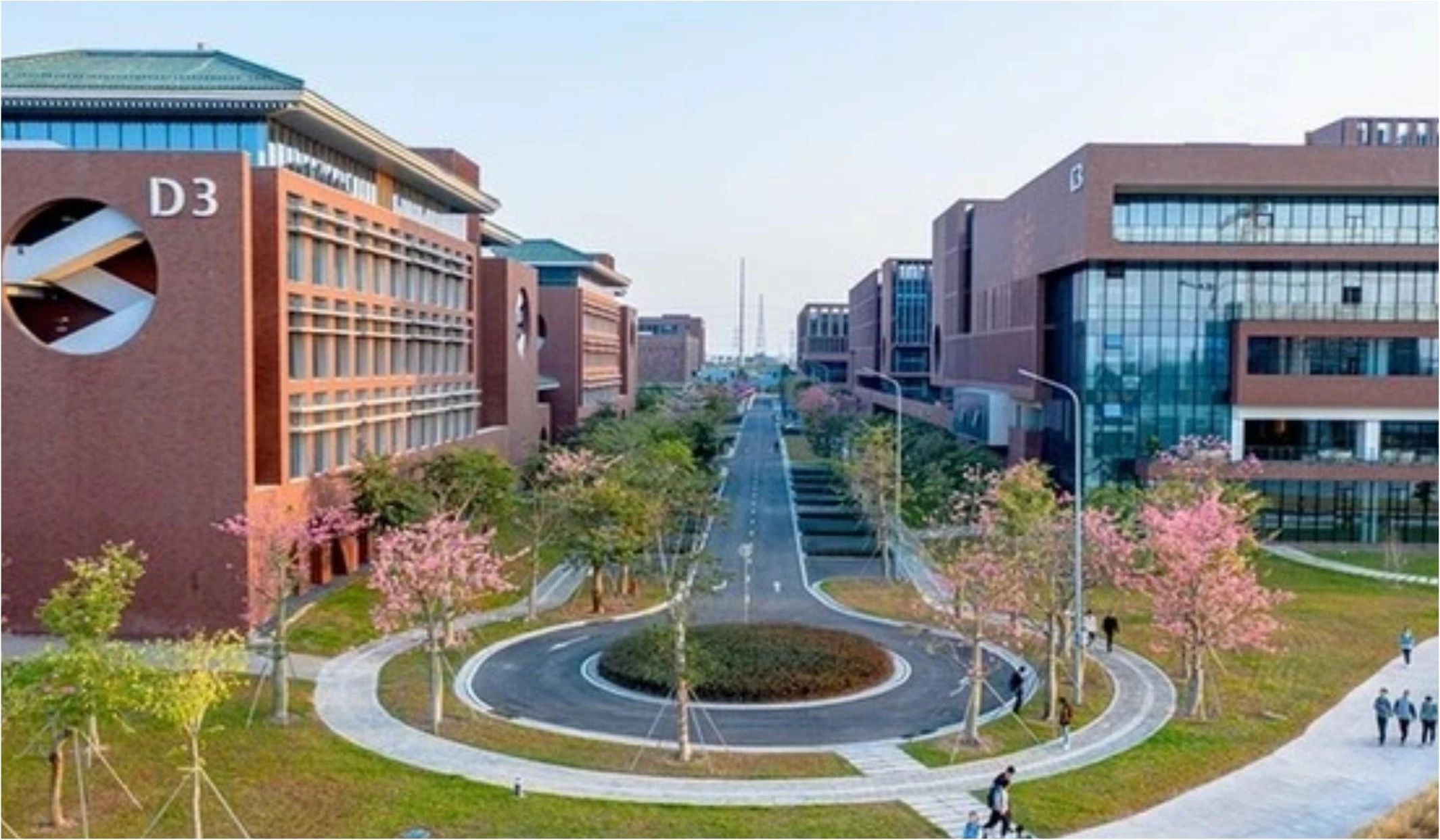 University campus buildings with a circular facade emblem and landscaped central avenue in Guangzhou