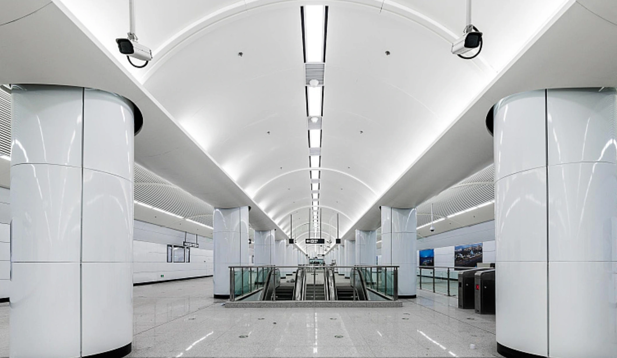 Arched white aluminum ceiling and cylindrical column covers in a Suzhou metro station