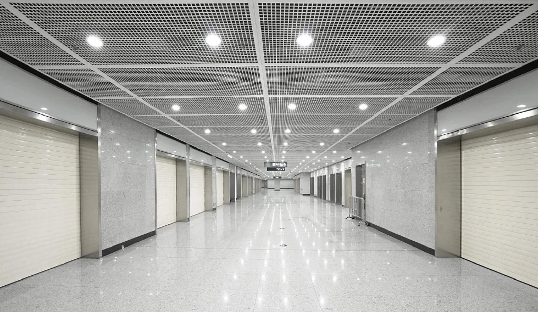 Fine mesh ceiling panels with circular downlights along a Xiamen metro concourse