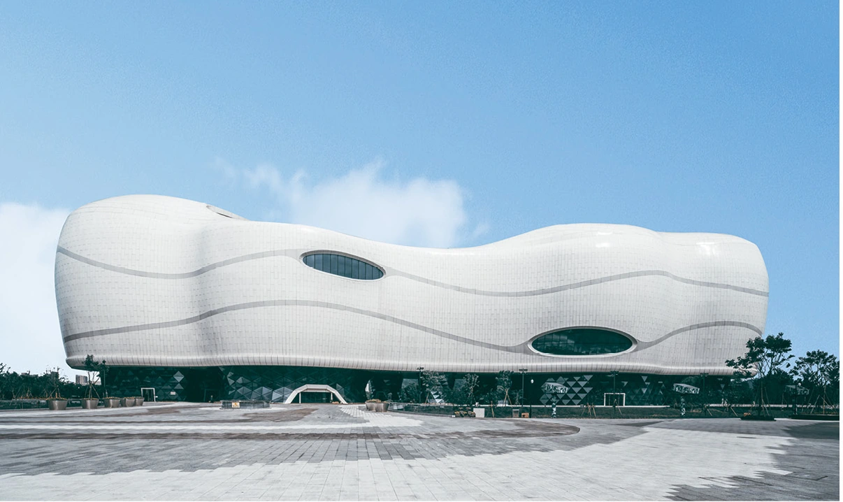 White curved aluminum cladding wrapping a museum exterior with oval window openings
